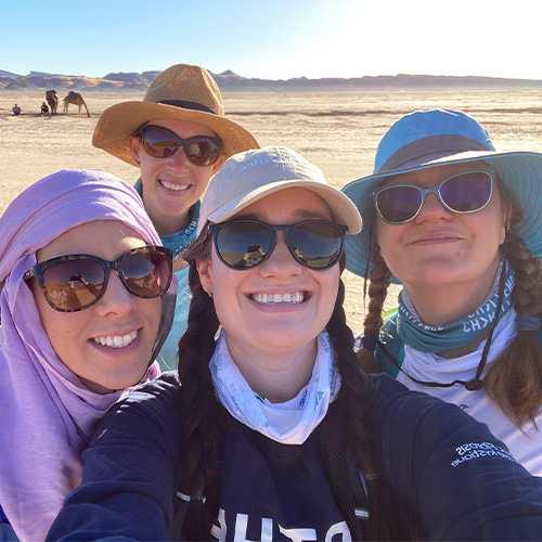 Lex and other trekkers smiling in the desert.